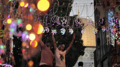 خلفية لزينة رمضان و مجموعة من الشباب يعلقونها في الطريق.